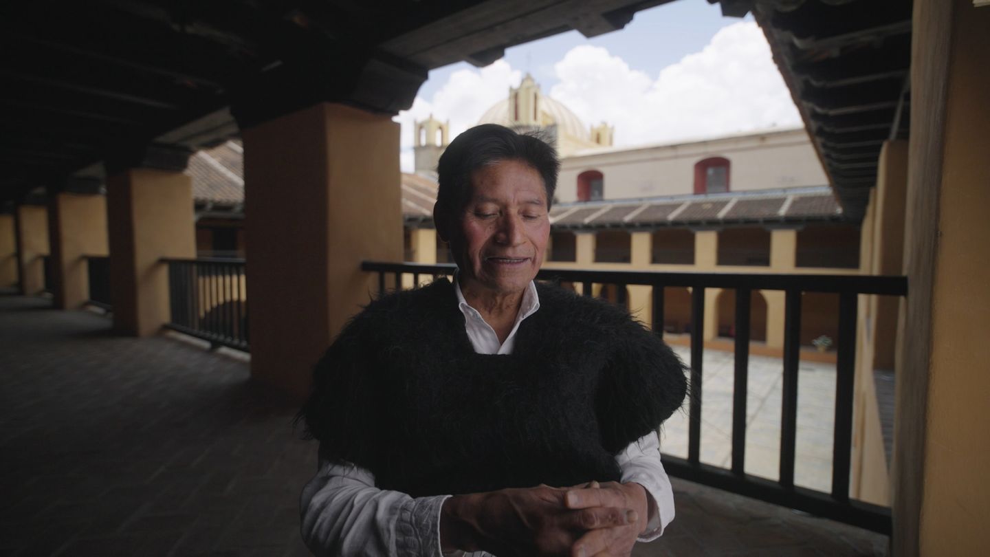 Un hombre se asoma al corredor alto de un edificio colonial.