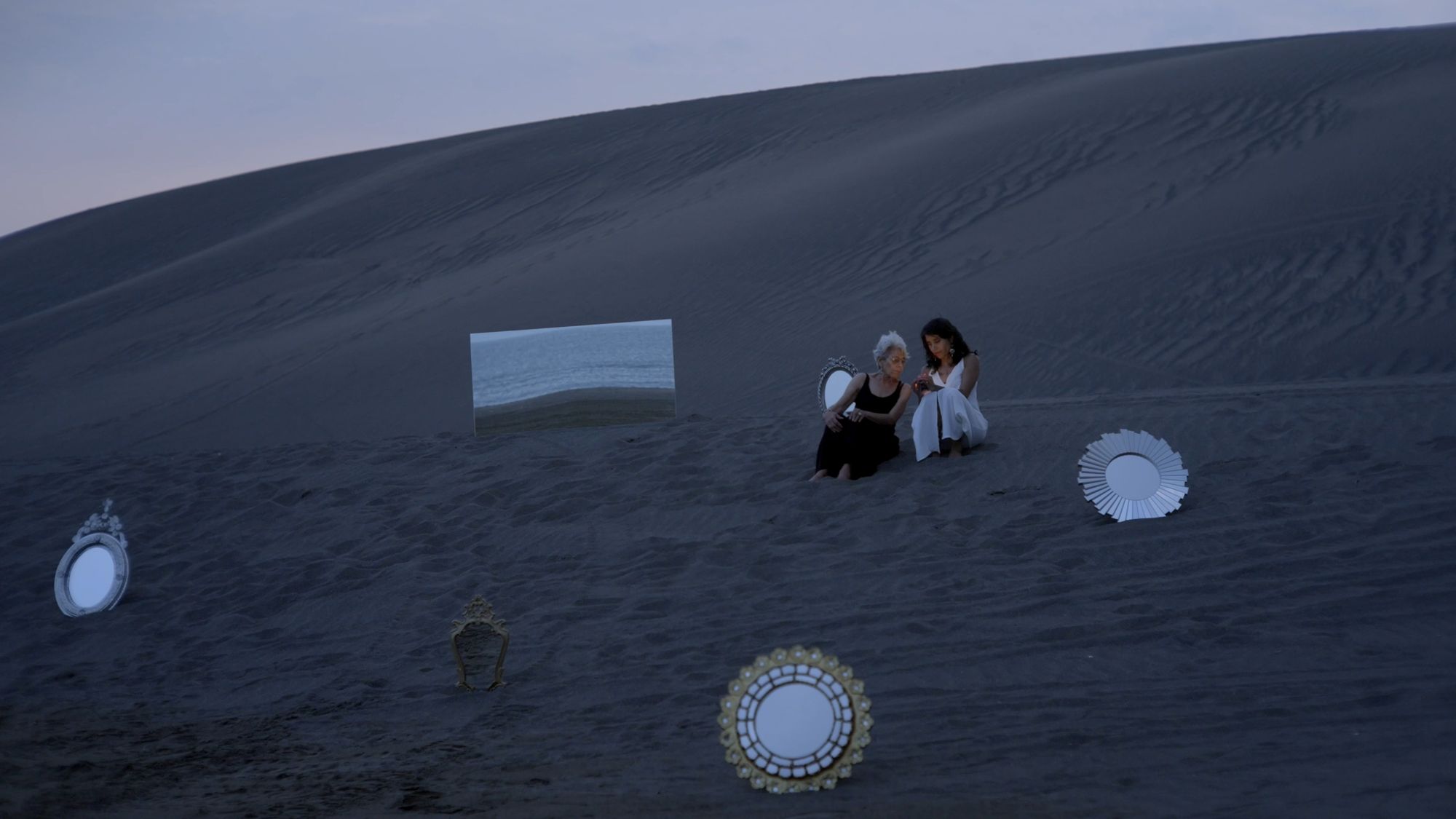 Duna al crepúsculo con espejos dispuestos sobre la arena.