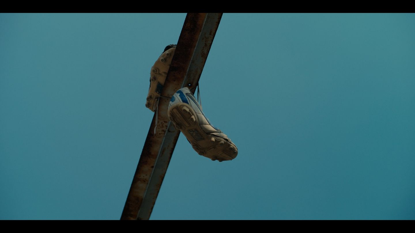 Un par de zapatos colgados de un cable, recortados contra el cielo azul.