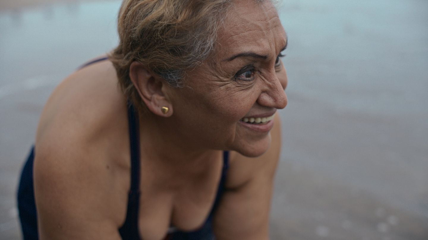 Retrato cercano de una mujer mayor en la playa con luz suave de atardecer.